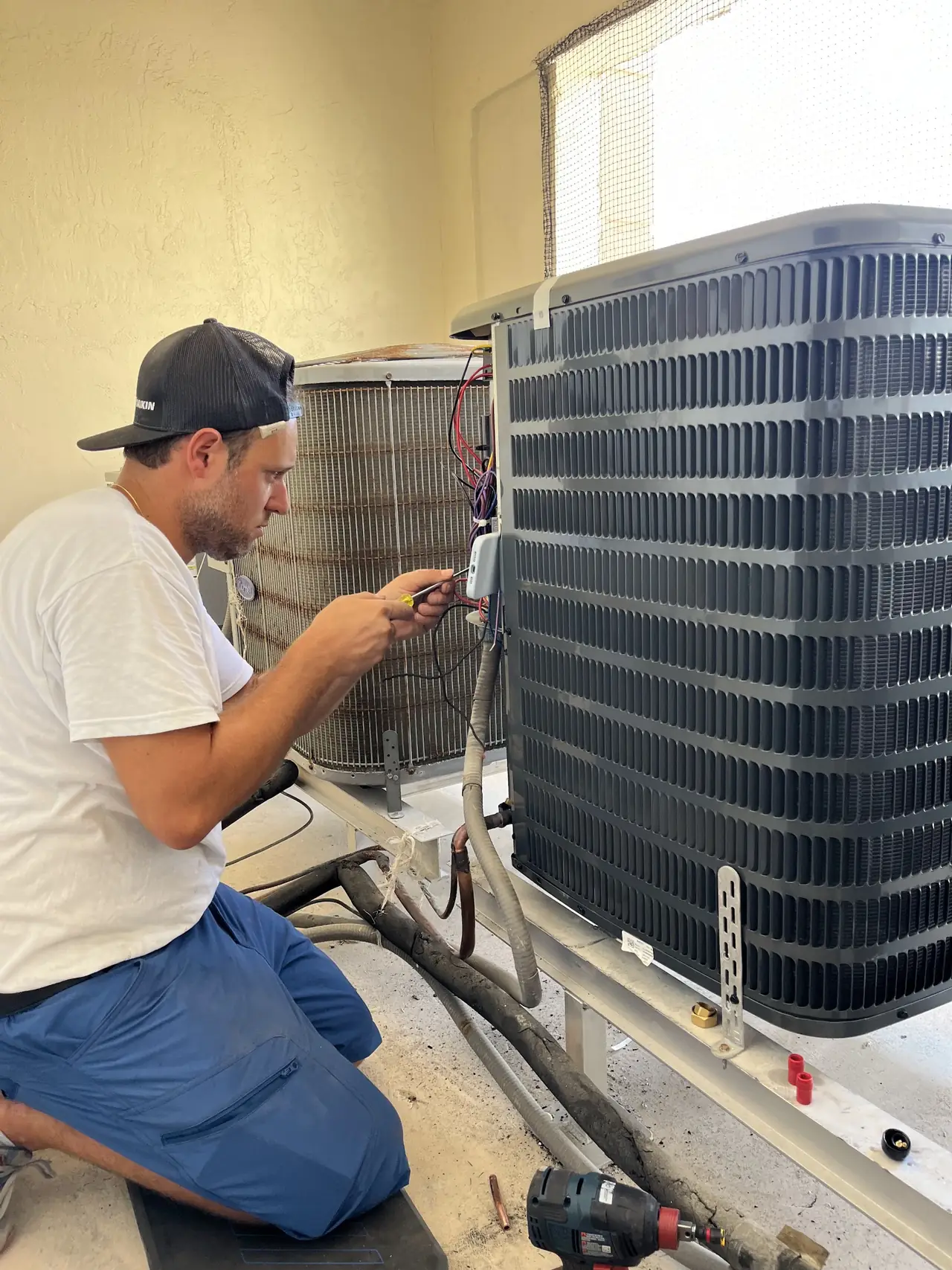 Technician checking refrigerant lines on an outdoor AC unit