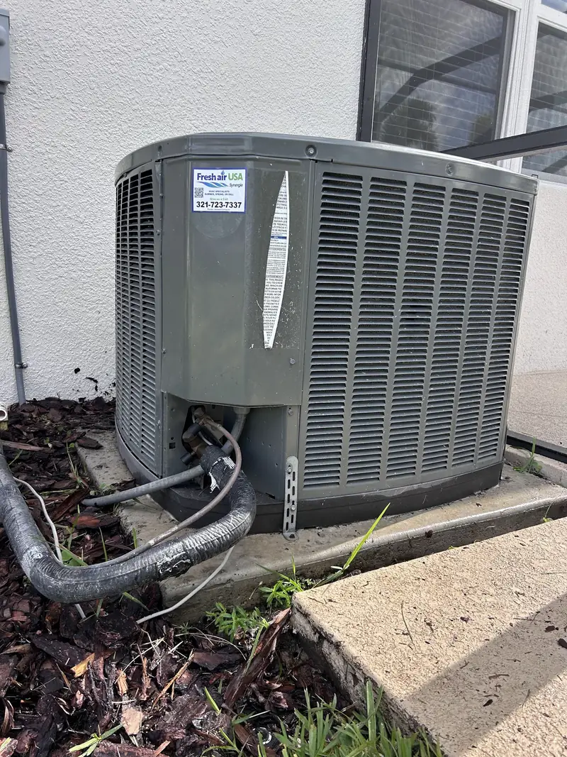 Condenser with refrigerant lines beside a stucco wall