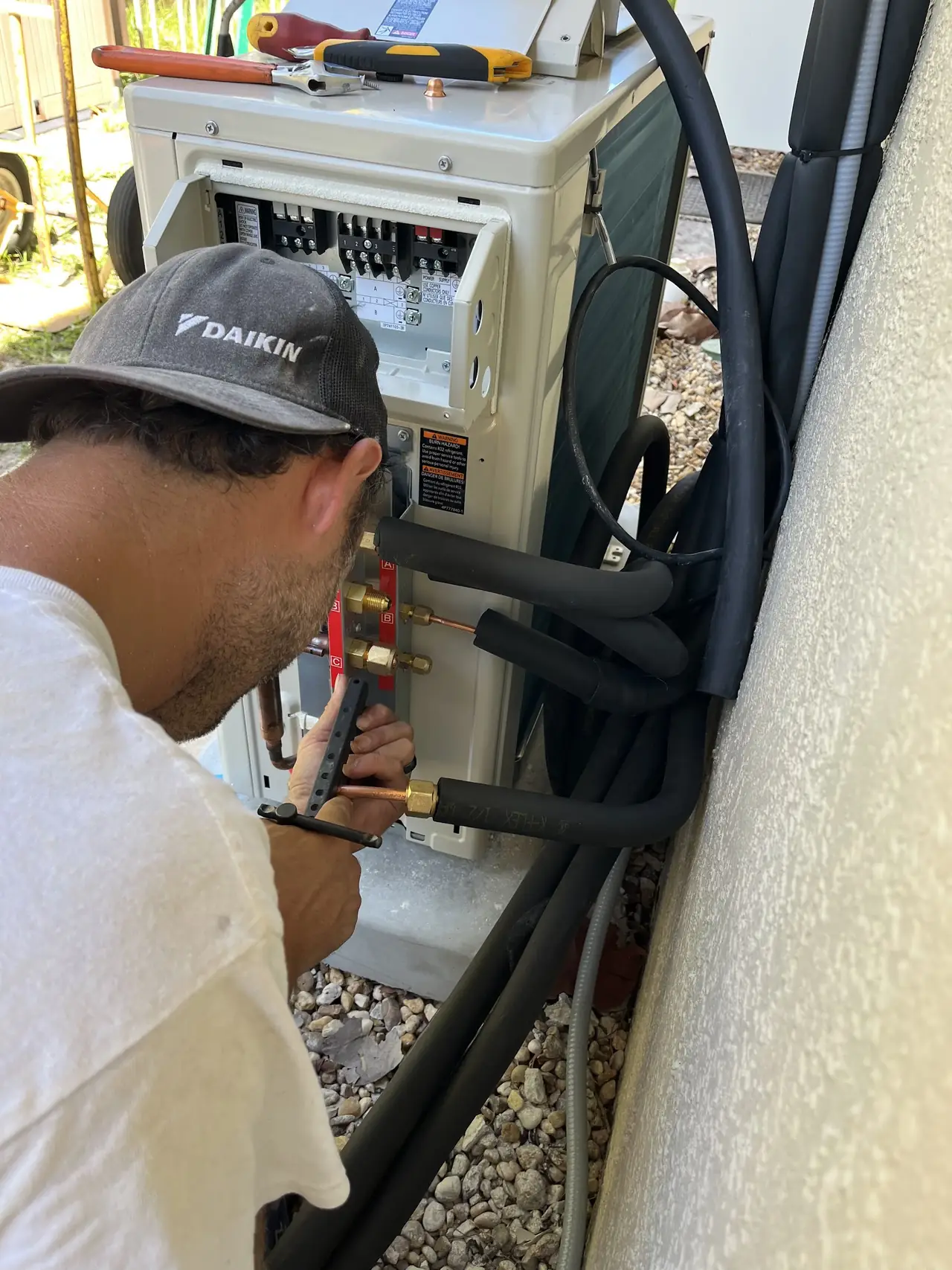 Technician testing electrical connections at a condensing unit