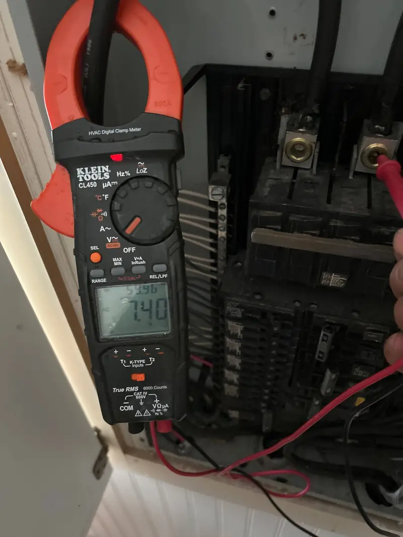 Clamp meter reading amperage at an electrical panel
