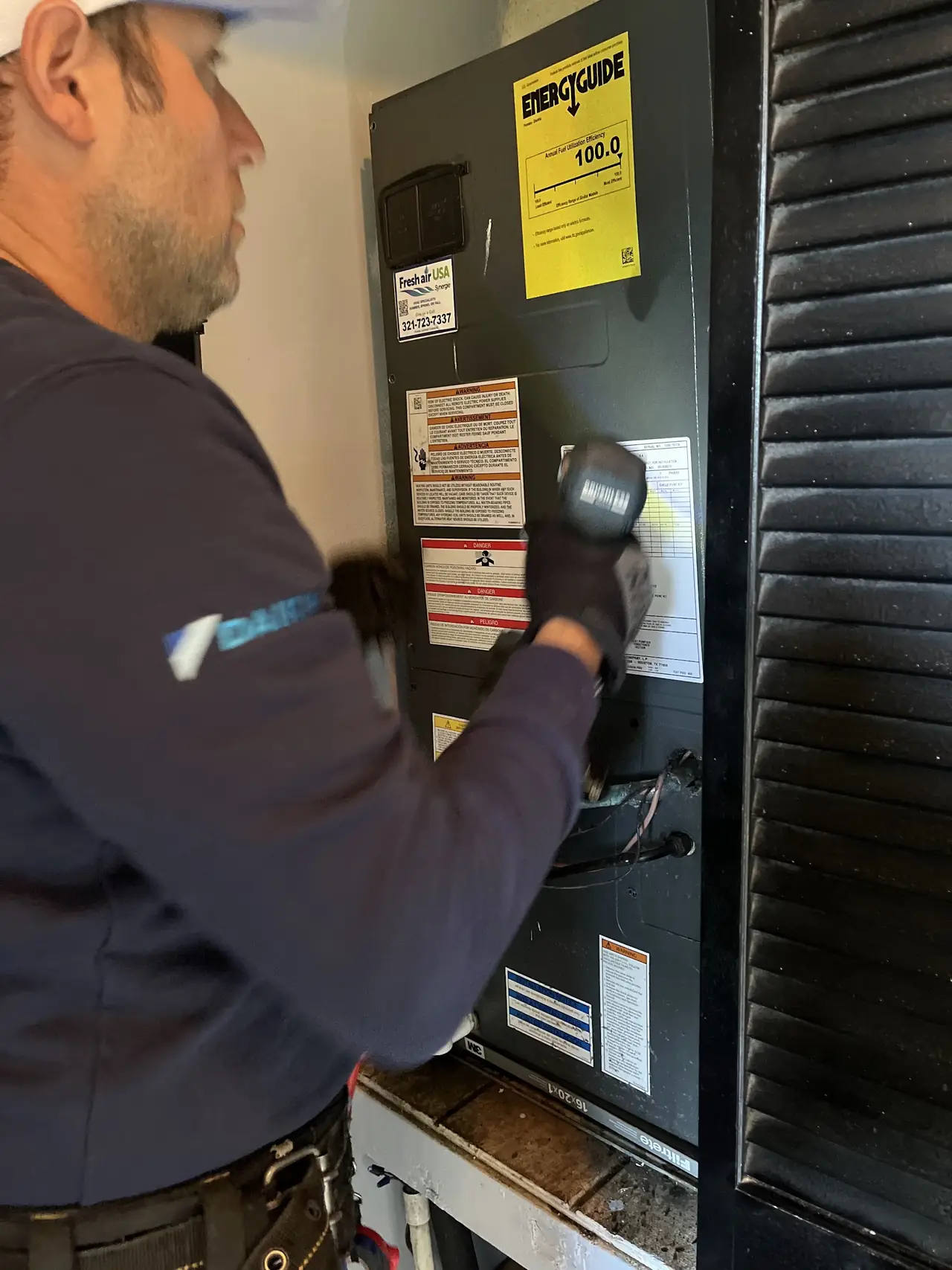 Technician inspecting an electrical panel with a flashlight