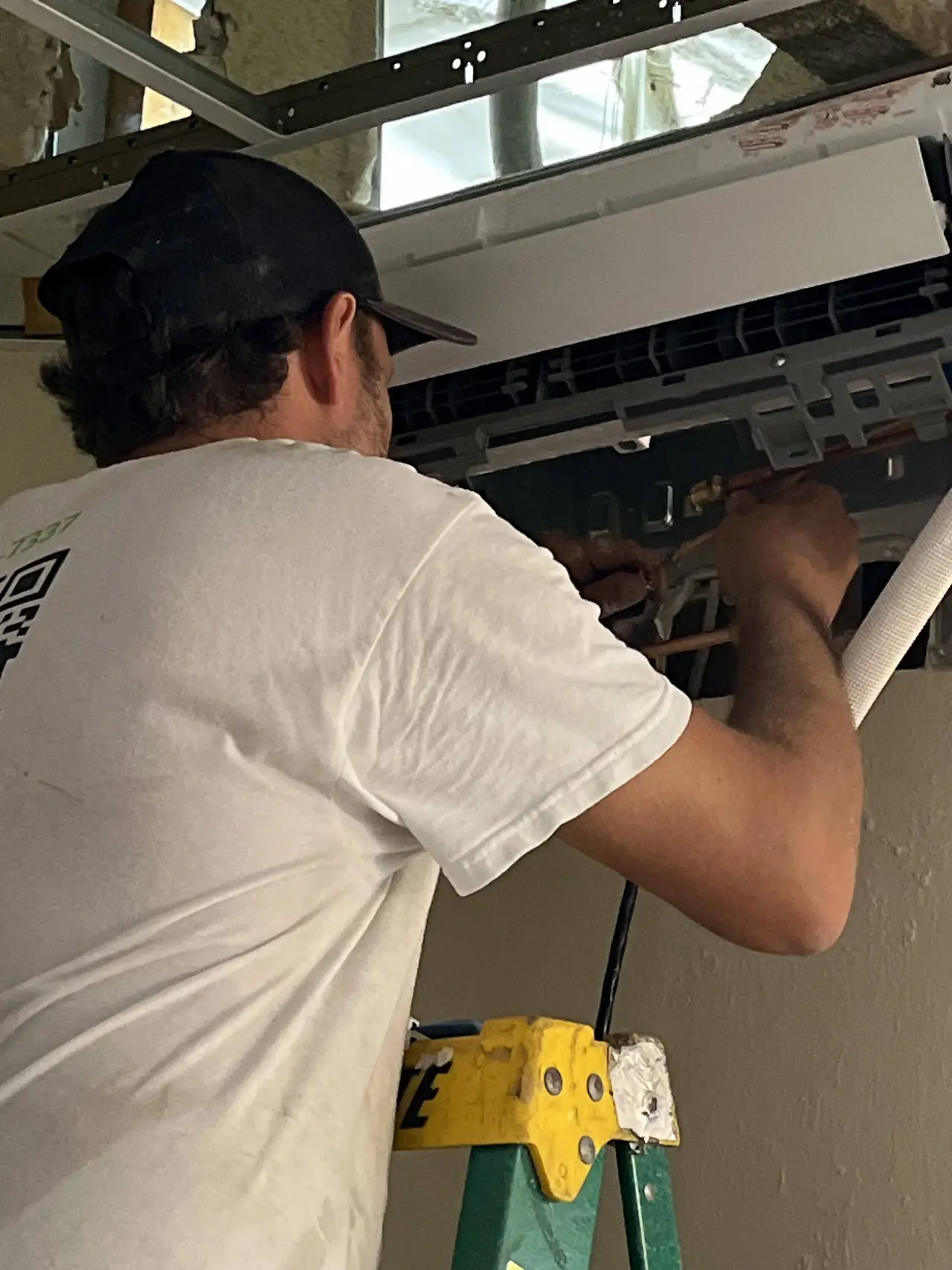 Technician installing a ceiling-mounted air handler