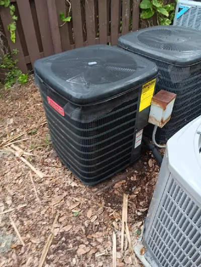 Two outdoor condensers behind a residential fence