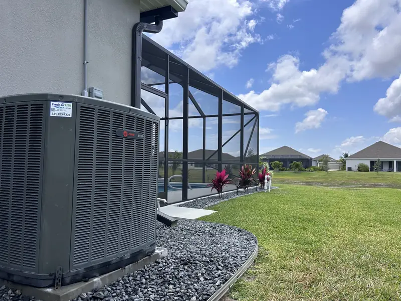 Condenser positioned beside a screened pool enclosure