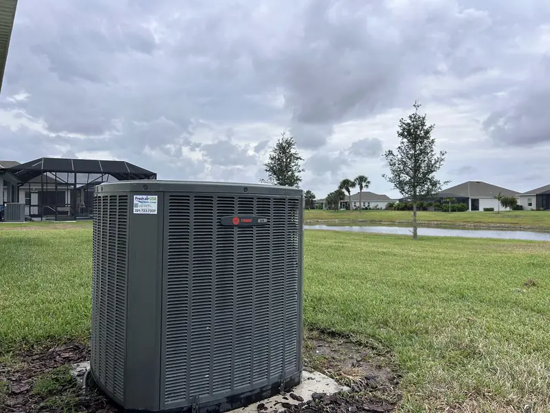 Condenser unit on a concrete pad beside a lawn