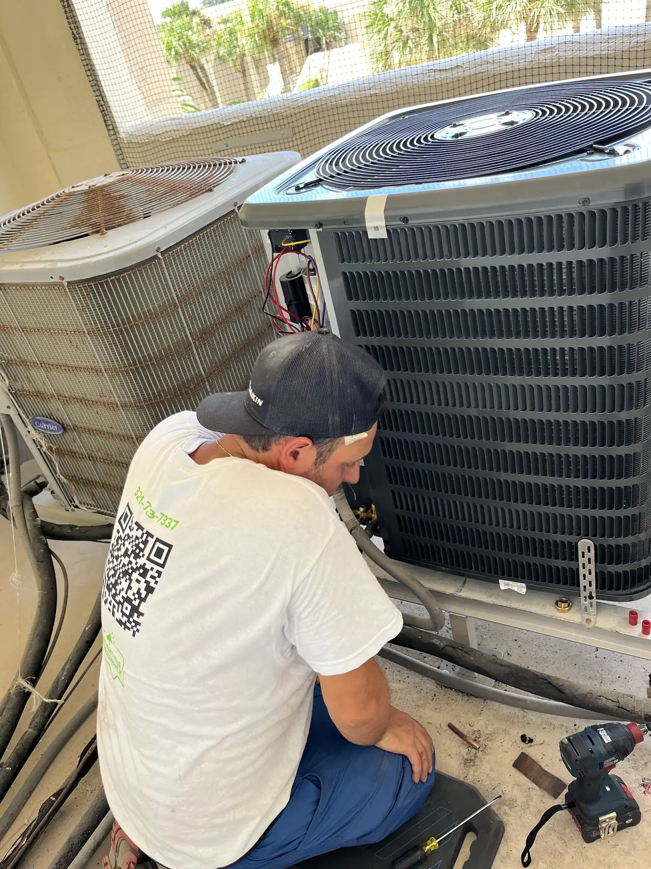 Technician servicing a condenser coil in a screened yard